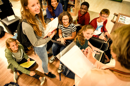 adolescent school students smiling and talking with a teacher